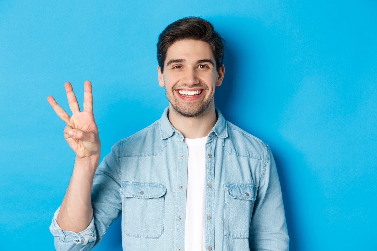 Homme sur fond bleu lève 3 doigts pour 3 opérateurs avec forfaits 300 Go en 5G à 15€